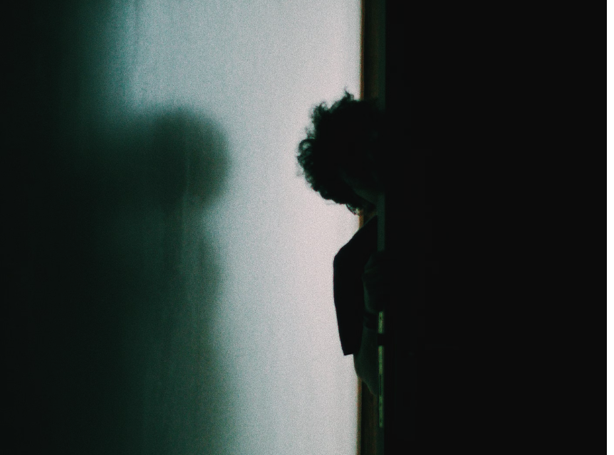 Person peeking around the door into a dark room